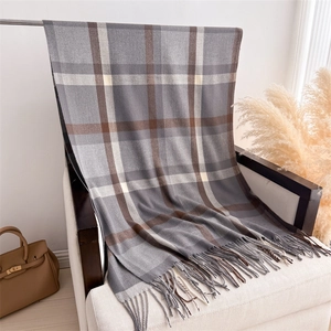 Close-up of winter plaid scarf with fringe detail in grey, brown, and beige tones