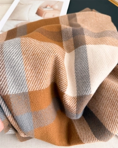 Close-up of classic plaid scarf showing caramel and grey twill cashmere-like fabric