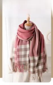 Close-up of pink and brown plaid winter scarf texture with soft tassels on the edge