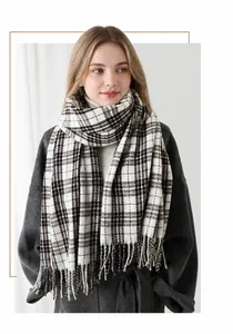 Close-up of classic plaid patterned scarf with long fringe detail on grey wool coat