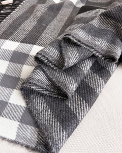 Detail of plaid cashmere-feel scarf with black and white geometric pattern and tassels