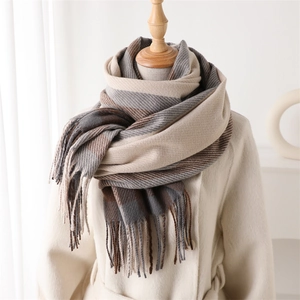 Detail of plaid tassel scarf with soft cashmere-like texture on a beige wool coat