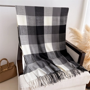 Détail d'une écharpe à carreaux noirs et blancs avec franges sur un fauteuil