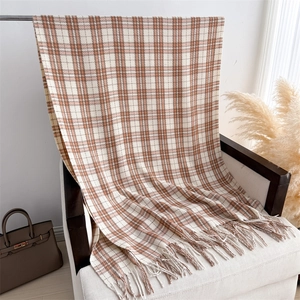 Detail of checkered cashmere-feel scarf with fringes on a white classic armchair