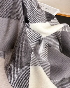 Gros plan sur l'écharpe à carreaux gris montrant la texture douce du tissage chevron