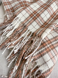 Detail of orange and brown plaid cashmere scarf texture with soft fringe edges