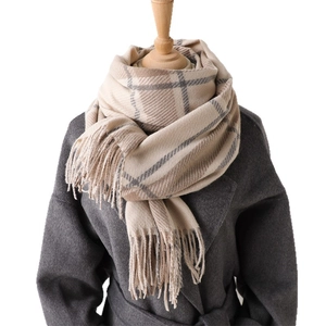 Classic British plaid scarf in beige and grey with elegant tassels on a mannequin