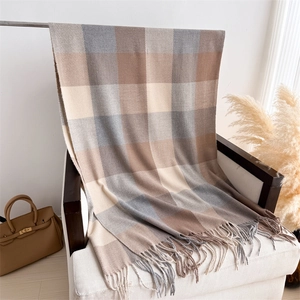 Détail du motif à carreaux gris et beige avec franges douces sur un fauteuil