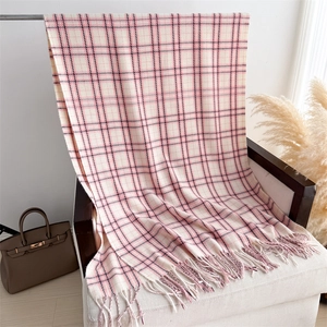 Detail of soft plaid scarf with fringe texture on a white sofa for autumn and winter