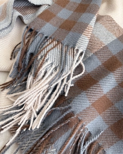 Macro detail of plaid cashmere shawl showing twill weave texture and long fringe tassels