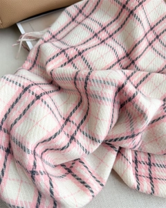 Close-up of pink plaid cashmere-feel scarf showing soft texture and tassel details