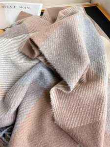 Gros plan sur une écharpe épaisse à carreaux avec tissage à chevrons tons beige et gris