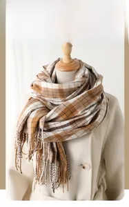 Classic checkered winter scarf with fringes styled on a coat in warm brown and beige