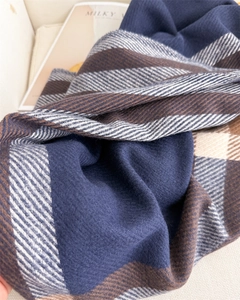 Close-up of thick plaid cashmere-like scarf with warm navy blue and brown fringe texture