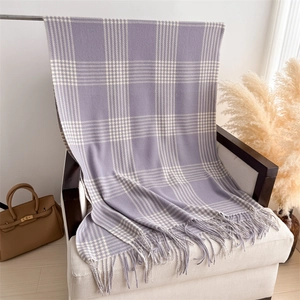 Detail shot of lavender and white plaid scarf with fine fringe on a cream sofa