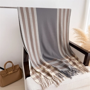 Detailed view of plaid cashmere feel scarf with fringe on a white armchair