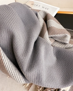 Close-up of herringbone weave cashmere-like shawl with classic fringe and dual-tone stripes