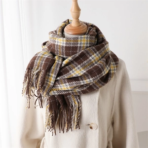 Detailed close-up of plaid cashmere-like scarf fringe and thick knit pattern in warm tones