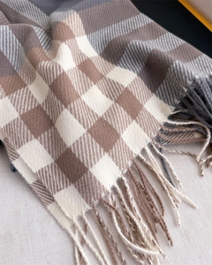Detail shot of plaid cashmere-like scarf showing soft texture and fringe tassels