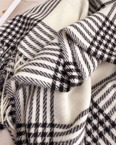 Close-up of black and white plaid scarf featuring soft cashmere-like texture and tassels