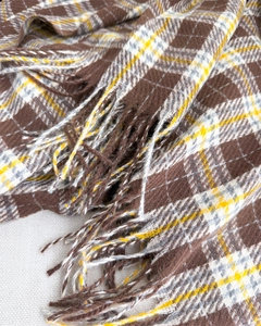 Close-up of thick plaid cashmere feel scarf with coffee and yellow fringe details