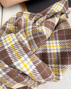 Detailed texture of brown plaid scarf with soft cashmere-like fabric and elegant fringe