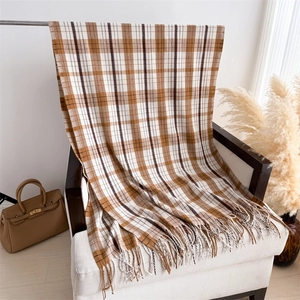 Detail of soft checkered scarf with tassels draped on chair in a warm home setting
