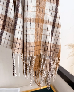 Detail of plaid scarf featuring camel and brown check patterns with soft fringe edges