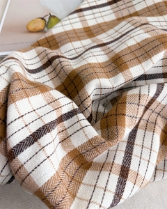 Macro shot of plaid scarf detail showing premium herringbone weave and warm fabric texture