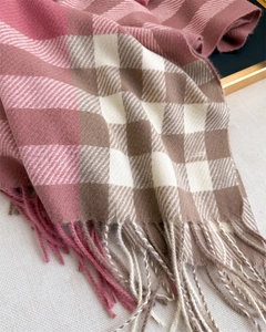 Close-up of pink and beige plaid shawl scarf with soft texture and tassel fringe details