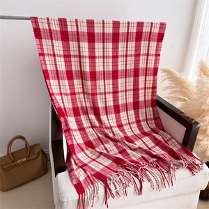 Detail shot of red and white plaid scarf with long tassels on a cozy white armchair