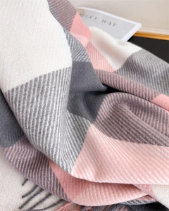 Gros plan d'une écharpe à carreaux rose et gris, texture cachemire douce et franges