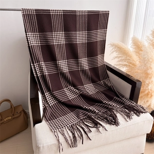 Detailed close-up of dark brown plaid cashmere scarf with hand-twisted tassel fringe