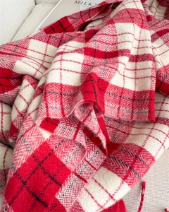 Detail of red and white plaid knit scarf with soft cashmere-like texture and tassels
