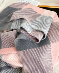 Gros plan sur la texture d'une écharpe à carreaux rose et gris avec bords à franges doux