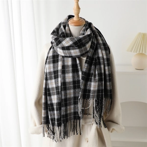 Plaid cashmere-like scarf with fringe detail over a beige coat for a stylish winter look