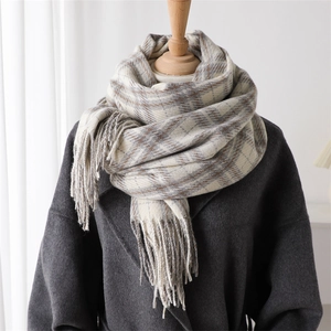 Detail of classic beige and grey plaid scarf with long tassels on a winter wool coat