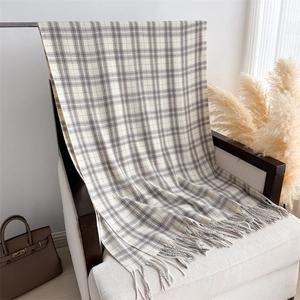 Detail of plaid scarf with tassels draped on a classic chair in a cozy setting
