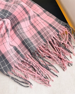 Detailed view of pink and grey plaid scarf with soft fringe edges and woven texture
