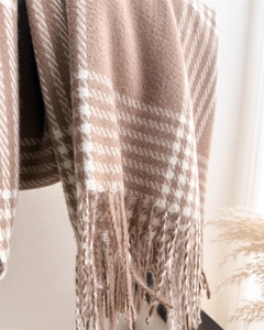 Detail of warm brown and cream plaid scarf featuring soft cashmere texture and fringe