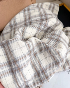 Macro detail of soft cashmere-feel scarf fabric with elegant grey and brown plaid pattern