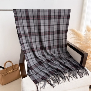 Detailed texture of black grey red plaid scarf with tassel fringe on a white chair