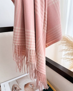 Detailed view of pink and white plaid scarf with soft fringe on a cozy armchair