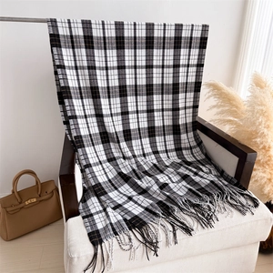 Detailed view of black and white plaid cashmere scarf with soft fringe on a chair
