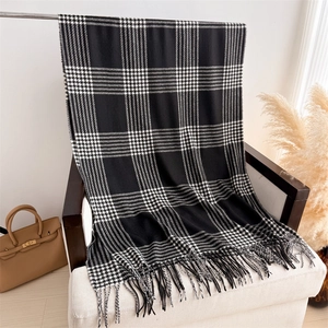 Detail of checkered cashmere shawl draped on a chair with fringe accents