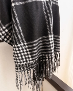 Detail showing soft texture of black and white plaid scarf with long fringes