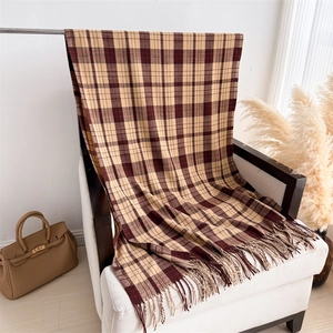Close-up of beige and reddish-brown plaid scarf with fringe details on a white wood chair
