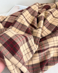Macro detail of soft cashmere-like knit fabric with classic beige and brown plaid pattern