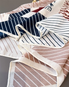Detail of geometric pattern and herringbone texture on the folded silk-feel scarf scarf
