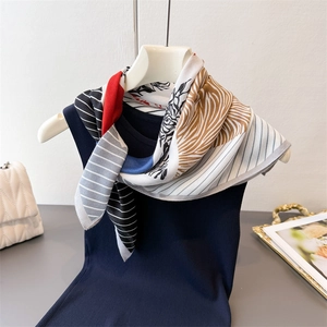 Detail of geometric pattern silk scarf styled over a navy knit top with a classic print